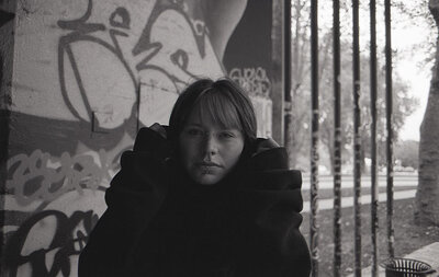 Regard intense Portrait rapproché en noir et blanc d'une jeune femme avec des piercings faciaux, ajustant sa capuche et regardant fixement l'objectif.